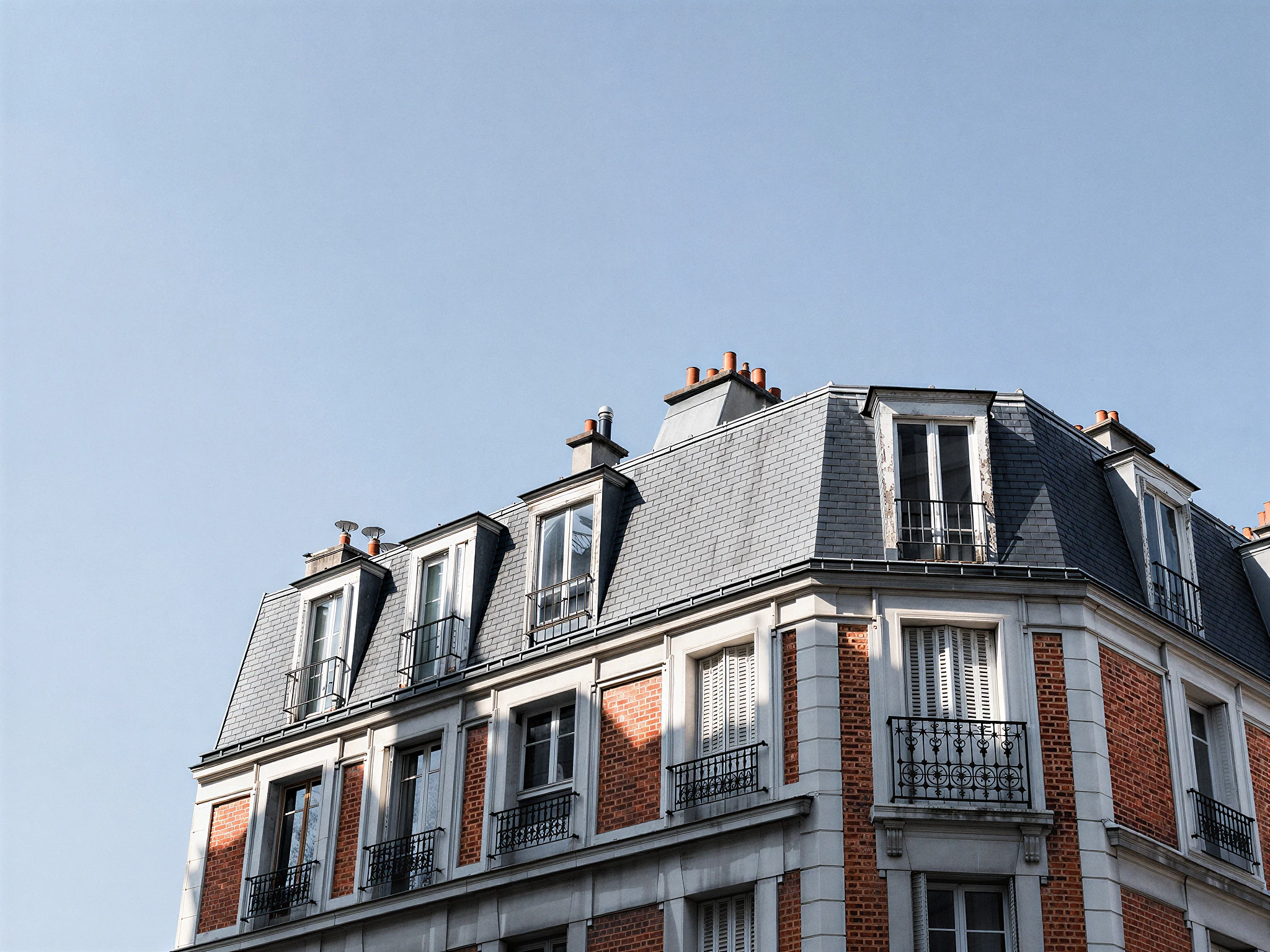 Façade et toit en mansarde d'un immeuble parisien en brique et pierre