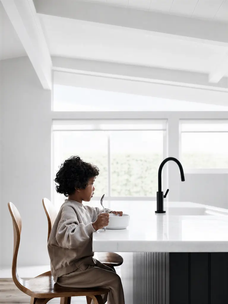 Enfant assis à un comptoir de cuisine moderne et épuré avec un robinet noir