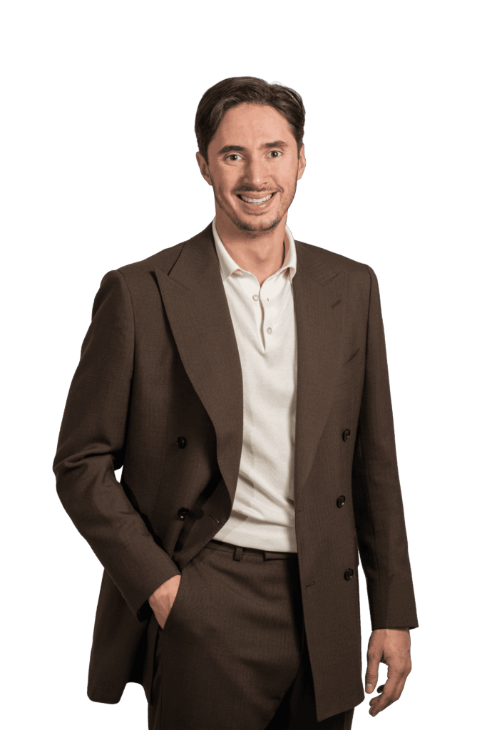 Portrait d'un homme en costume croisé marron et polo blanc sur fond noir.